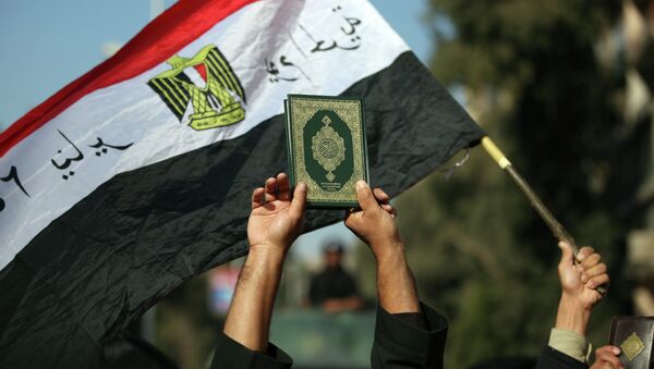 An Egyptian man holds up the a copy of Quran - Sputnik International