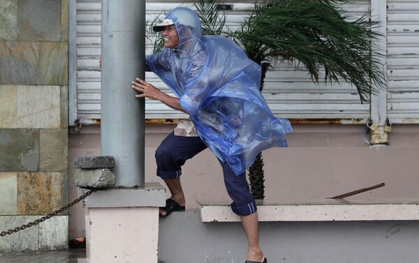 A man holds on to a pole as strong winds blow brought by Typhoon Hagupit in Legazpi, Albay province, eastern Philippines on Sunday, Dec. 7, 2014 - Sputnik International