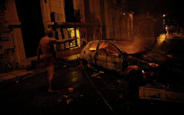 A local resident in his underwear tries to extinguish a burning car used by protesters as a barricade, during riots in Athens neighborhood of Exarchia - Sputnik International