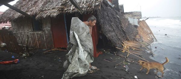 A Filipino man carries a dirty plastic sheet from his house after strong waves from Typhoon Hagupit A Filipino man carries a dirty plastic sheet from his house after strong waves from Typhoon Hagupit - Sputnik International