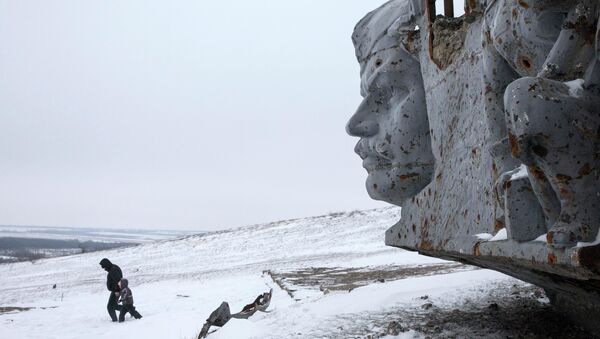 A man and a child walk in the snow at the destroyed war memorial at Savur-Mohyla, a hill east of the city of Donetsk - Sputnik International