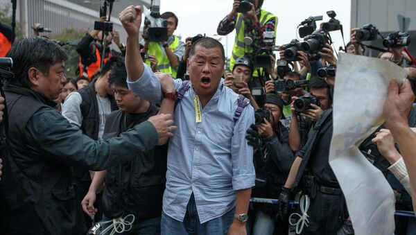 Tycoon and Apple Daily Newspaper owner shouts slogan before he is taken away by police officer at an area previously blocked by pro-democracy supporters, outside the government headquarters in Hong Kong - Sputnik International