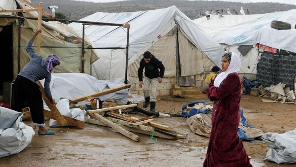 A woman walks past Syrian refugees dismantling their tents at a makeshift settlement in al-Rafid town, in the Bekaa valley - Sputnik International