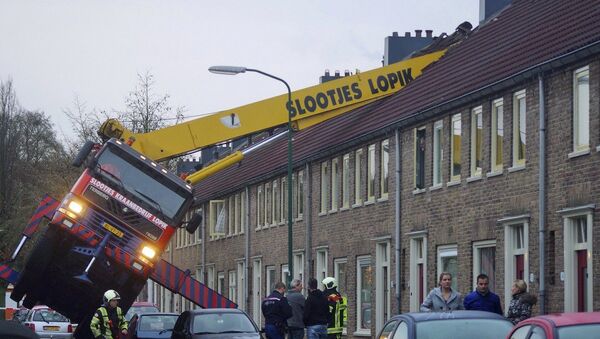 A crane which crashed into the roof of a house is seen following an unusual marriage proposal by a man who wished to be lifted in front of the bedroom window of his girlfriend to ask for her hand in marriage, in the central Dutch town of IJsselstein, Saturday Dec. 13, 2014 - Sputnik International