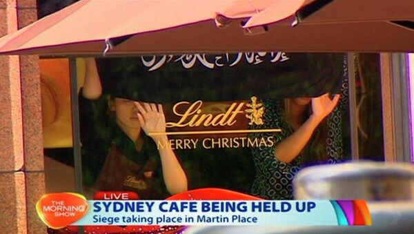 This image taken from video shows people holding up what appeared to be a black flag with white Arabic writing on it, inside a cafe in Sydney, Australia Monday, Dec. 15, 2014 - Sputnik International