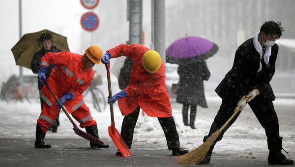 Railway station workers shove snow from the street in Yokohama, Japan, Saturday. - Sputnik International