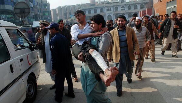 A man carries a student, who was injured during an attack by Taliban gunmen on the Army Public School, after he received treatment at a hospital in Peshawar, December 16, 2014 - Sputnik International