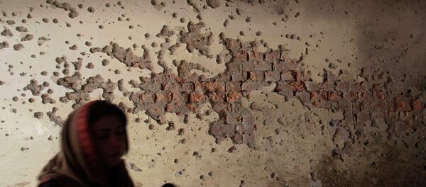 A local reporter walks past a damaged wall A local reporter walks past a damaged wall - Sputnik International