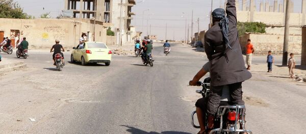 A man holds up a knife as he rides on the back of a motorcycle in Northern Syria. A man holds up a knife as he rides on the back of a motorcycle in Northern Syria. - Sputnik International