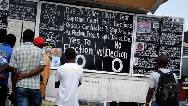 Bystanders read the headlines illustrating the battle over the holding of elections in Liberia amid the Ebola crisis at a street side chalkboard newspaper in Monrovia. - Sputnik International