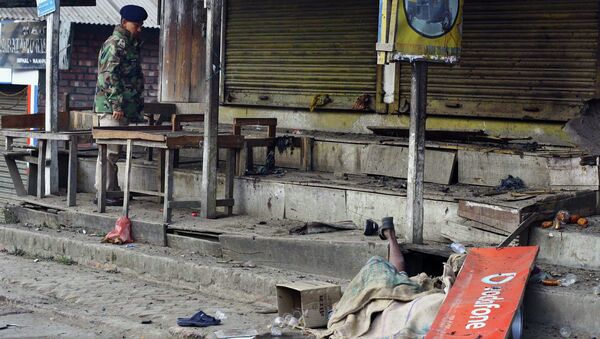 The body of a blast victim is seen as an Indian policeman stands at the site of an explosion in Imphal, the capital of Manipur state, India, Sunday, Dec. 21, 2014 - Sputnik International