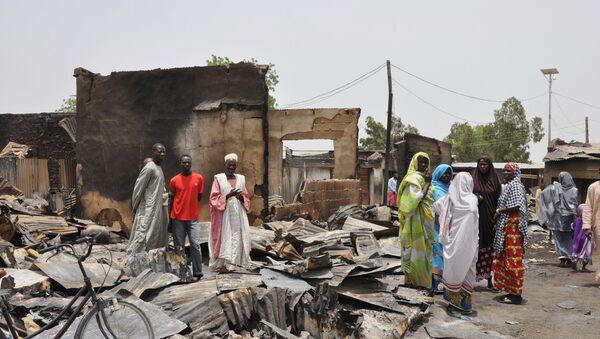 In this Sunday, May 11, 2014 file photo, people stand outside burnt houses following an attack by Islamic militants in Gambaru, Nigeria. - Sputnik International