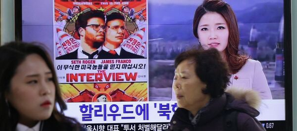 People walk past a TV screen showing a poster of Sony Picture's The Interview in a news report, at the Seoul Railway Station in Seoul, South Korea, Monday, Dec. 22, 2014 - Sputnik International