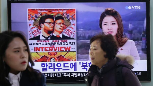 People walk past a TV screen showing a poster of Sony Picture's The Interview in a news report, at the Seoul Railway Station in Seoul, South Korea, Monday, Dec. 22, 2014 - Sputnik International