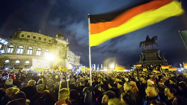 Participants hold German national flags during a demonstration organised by anti-immigration group PEGIDA, a German abbreviation for Patriotic Europeans against the Islamisation of the West, outside Semperoper opera house in Dresden December 22, 2014. - Sputnik International