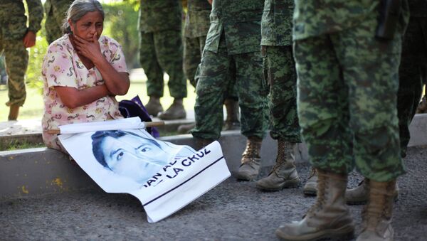 In this Dec. 18, 2014 photo, a woman sits next to Mexican army soldiers standing in front of the entrance to the 27th Infantry Battalion base in Iguala, Mexico - Sputnik International