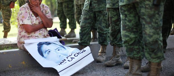 In this Dec. 18, 2014 photo, a woman sits next to Mexican army soldiers standing in front of the entrance to the 27th Infantry Battalion base in Iguala, Mexico In this Dec. 18, 2014 photo, a woman sits next to Mexican army soldiers standing in front of the entrance to the 27th Infantry Battalion base in Iguala, Mexico - Sputnik International