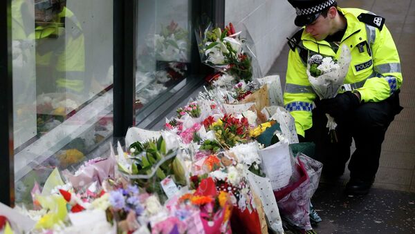 A police officer places flowers from a member of the public near the scene where a refuse truck crashed into pedestrians in George Square, Glasgow, Scotland December 23, 2014 - Sputnik International