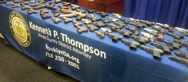 A collection of handguns and two assault rifles fill a table during a news conference at the Brooklyn District attorney's Office, Tuesday, Dec. 23, 2014 - Sputnik International