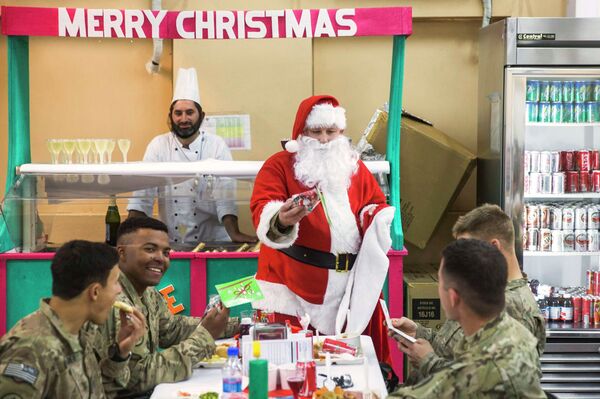 A U.S. soldier from the 3rd Cavalry Regiment dressed as Santa Claus greets fellow soldiers eating a Christmas day lunch on forward operating base Gamberi in the Laghman province of Afghanistan - Sputnik International