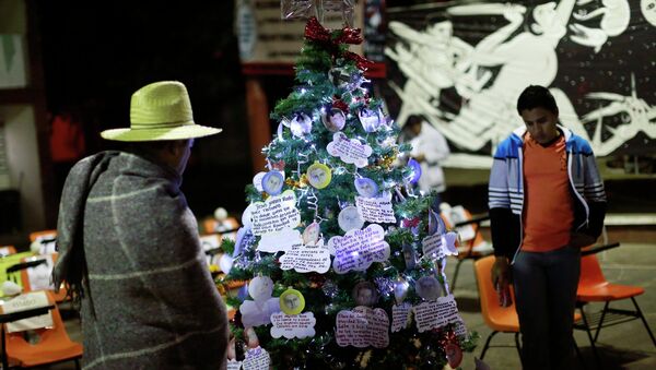 Men look at a Christmas tree, with pictures of the 43 missing trainee teachers, in the Ayotzinapa Teacher Training Raul Isidro Burgos College in Ayotzinapa, on the outskirts of Chilpancingo, Guerrero - Sputnik International