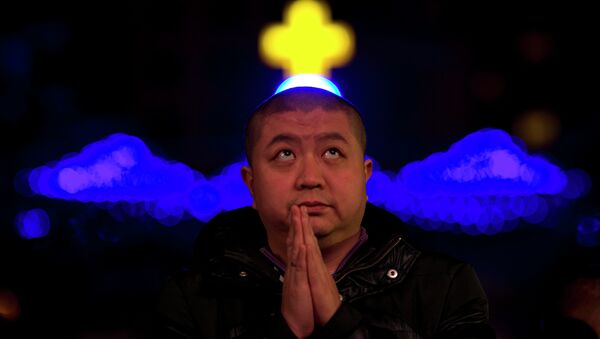 A Chinese man prays during a mass on the eve of Christmas at the South Cathedral official Catholic church in Beijing, China - Sputnik International