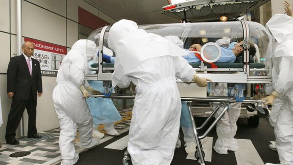 Watched by Tokyo Gov. Yoichi Masuzoe (far L), doctors in protective wear transport a person in a capsule-like sealed stretcher during a drill on Nov. 11, 2014 - Sputnik International