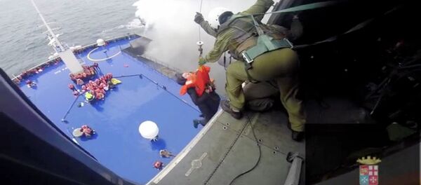 A person is lifted on an Italian Navy helicopter as the car ferry Norman Atlantic burns in waters off Greece December 28, 2014 in this handout video grab of the Italian Marina Militare - Sputnik International
