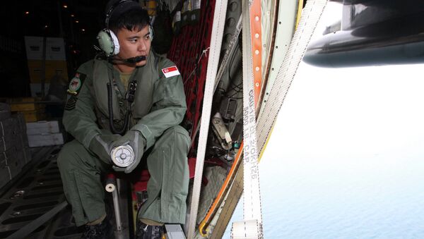 A member of the Republic of Singapore Air Force (RSAF) looks out into the waters, onboard a C-130 Hercules, during a Search and Locate operation for the missing AirAsia QZ8501 aircraft over an undisclosed search area December 29, 2014 - Sputnik International