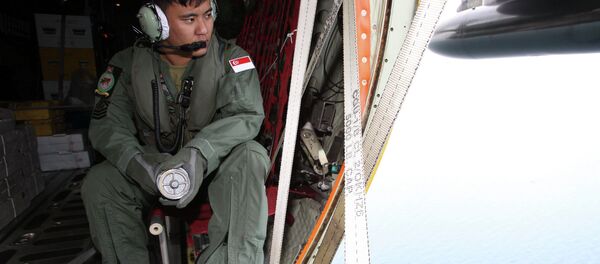 A member of the Republic of Singapore Air Force (RSAF) looks out into the waters, onboard a C-130 Hercules, during a Search and Locate operation for the missing AirAsia QZ8501 aircraft over an undisclosed search area December 29, 2014 - Sputnik International