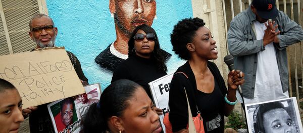 Demonstrators rally against the Missouri grand jury's decision to not indict Darren Wilson for his fatal shooting of Michael Brown, in front of a mural of Ezell Ford - Sputnik International