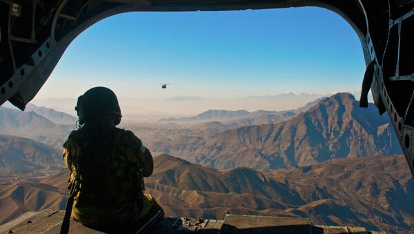 U.S. Army Spc. Devon Boxa, 7-158th Aviation Regiment, admires the Afghanistan landscape out the back door of her CH-47D Chinook helicopter as another Chinook follows - Sputnik International