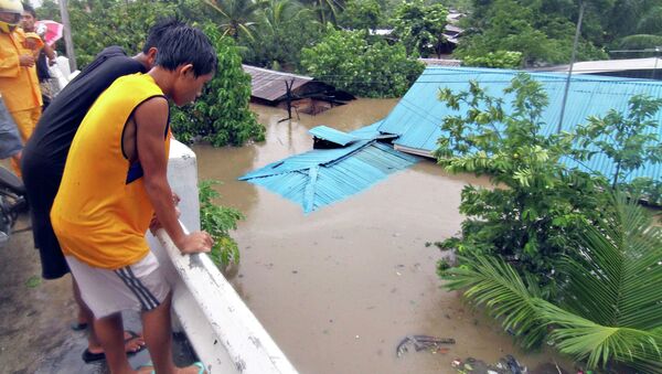 Residents stand on a bridge overlooking their homes submerged in floodwaters during heavy flooding brought by tropical storm Seniang in Misamis Oriental, on Mindanao island in southern Philippines December 29, 2014 - Sputnik International