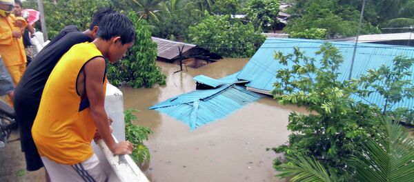 Residents stand on a bridge overlooking their homes submerged in floodwaters during heavy flooding brought by tropical storm Seniang in Misamis Oriental, on Mindanao island in southern Philippines December 29, 2014 - Sputnik International