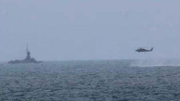 An MH-60R helicopter, attached to the USS Sampson (DDG 102), approaches an Indonesian patrol vessel while searching for debris, during the Indonesian-led search and recovery operations for the downed AirAsia flight QZ8501, in the Java Sea in this December 31, 2014 - Sputnik International