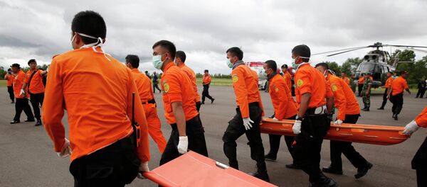 Indonesian Search and Rescue crews walk out to meet a helicopter carrying the bodies of two AirAsia passengers recovered from the sea, at Iskandar airport in Pangkalan Bun, Central Kalimantan, December 31, 2014 - Sputnik International