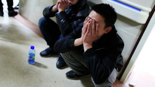 A friend of a victim covers his face as he waits outside a hospital where injured people of a stampede incident are treated, in Shanghai - Sputnik International