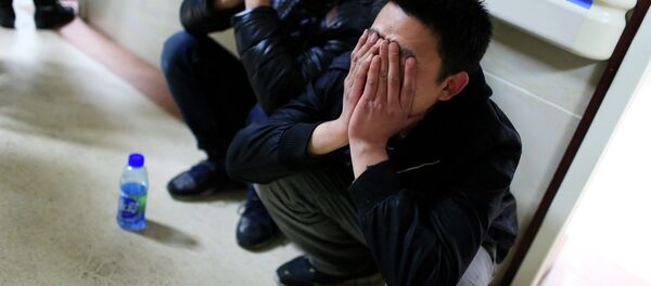 A friend of a victim covers his face as he waits outside a hospital where injured people of a stampede incident are treated, in Shanghai A friend of a victim covers his face as he waits outside a hospital where injured people of a stampede incident are treated, in Shanghai - Sputnik International