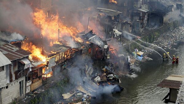 Firefighters fight the fire at shanties from a creek in suburban Quezon city, north of Manila, Philippines during an early morning fire Thursday, Jan. 1, 2015 - Sputnik International