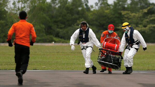 Rescue team members carry the dead body of a passenger of AirAsia flight QZ8501 - Sputnik International