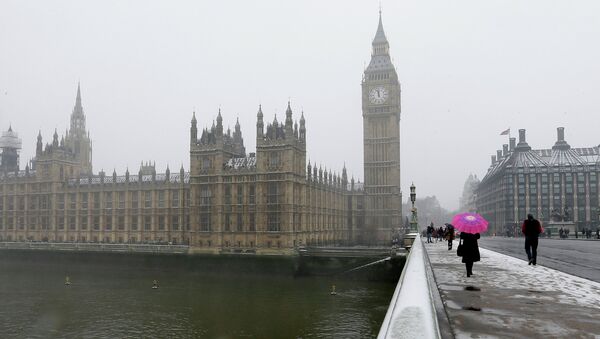 A woman carrying a pink umbrella walks across Westminster Bridge, with the Palace of Westminster in the background as it begins to snow in London, Friday, Jan. 18, 2013 - Sputnik International
