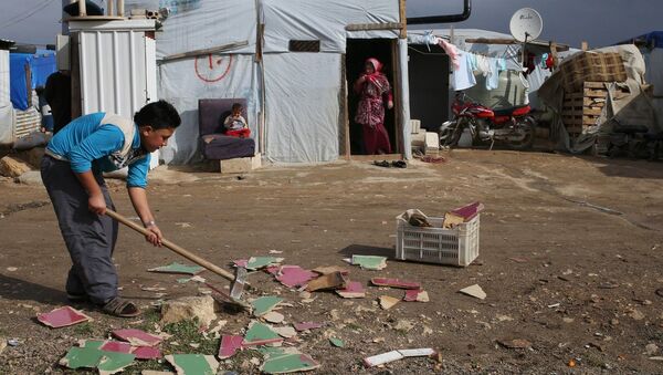 A Syrian boy chops scrap wood outside of his tent in preparation for the possibility of a snow storm at a refugee camp in Deir Zannoun village, Bekaa valley, Lebanon, Tuesday, Jan. 6, 2015 - Sputnik International