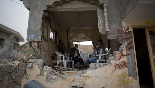 Palestinians sit in a room of their war-damaged house in the Shijaiyah neighborhood of Gaza City, Tuesday, Jan. 6, 2015 - Sputnik International