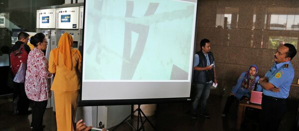 Officer of the National Search And Rescue Agency (BASARNAS) examines an underwater photo of the part of the wreckage of AirAsia. Officer of the National Search And Rescue Agency (BASARNAS) examines an underwater photo of the part of the wreckage of AirAsia. - Sputnik International