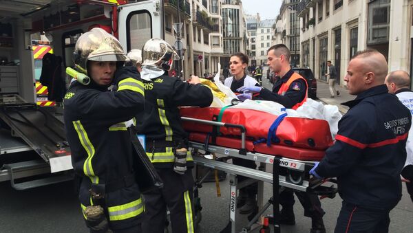 Firefighters carry an injured man on a stretcher in front of the offices of the French satirical newspaper Charlie Hebdo - Sputnik International