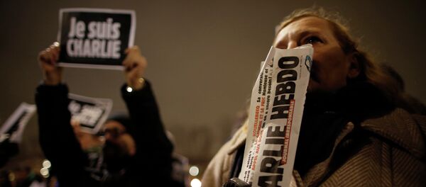 A man holds a copy of weekly satirical magazine Charlie Hebdo to pay tribute during a gathering at the Place de la Republique in Paris - Sputnik International