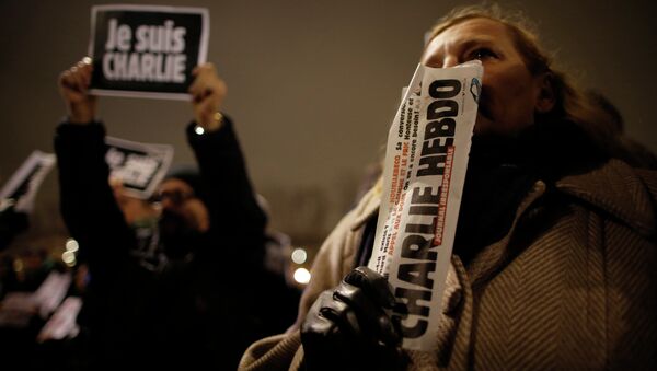 A man holds a copy of weekly satirical magazine Charlie Hebdo to pay tribute during a gathering at the Place de la Republique in Paris - Sputnik International