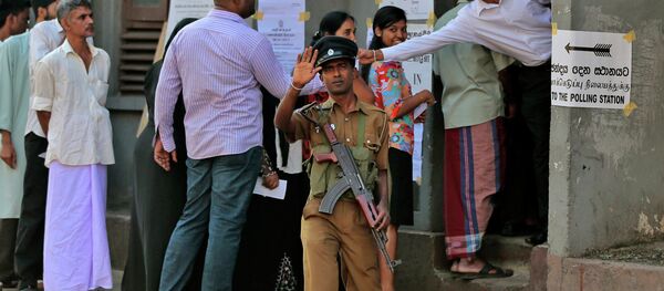 A Sri Lankan police officer gestures to the photographer demanding not to take photographs as people stand in a queue to cast their votes during the presidential elections in Colombo, Sri Lanka, Thursday, Jan. 8, 2015 A Sri Lankan police officer gestures to the photographer demanding not to take photographs as people stand in a queue to cast their votes during the presidential elections in Colombo, Sri Lanka, Thursday, Jan. 8, 2015 - Sputnik International