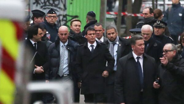 French Prime Minister Manuel Valls, front centre, walks with aids, outside the French satirical newspaper Charlie Hebdo's office, in Paris - Sputnik International