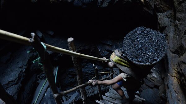 A miner slowly carries a heavy load of wet coal - Sputnik International